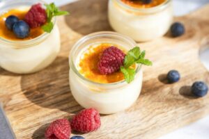 Close-up of a creme brulee dessert garnished with fresh sprig of mint and berries on a cutting board