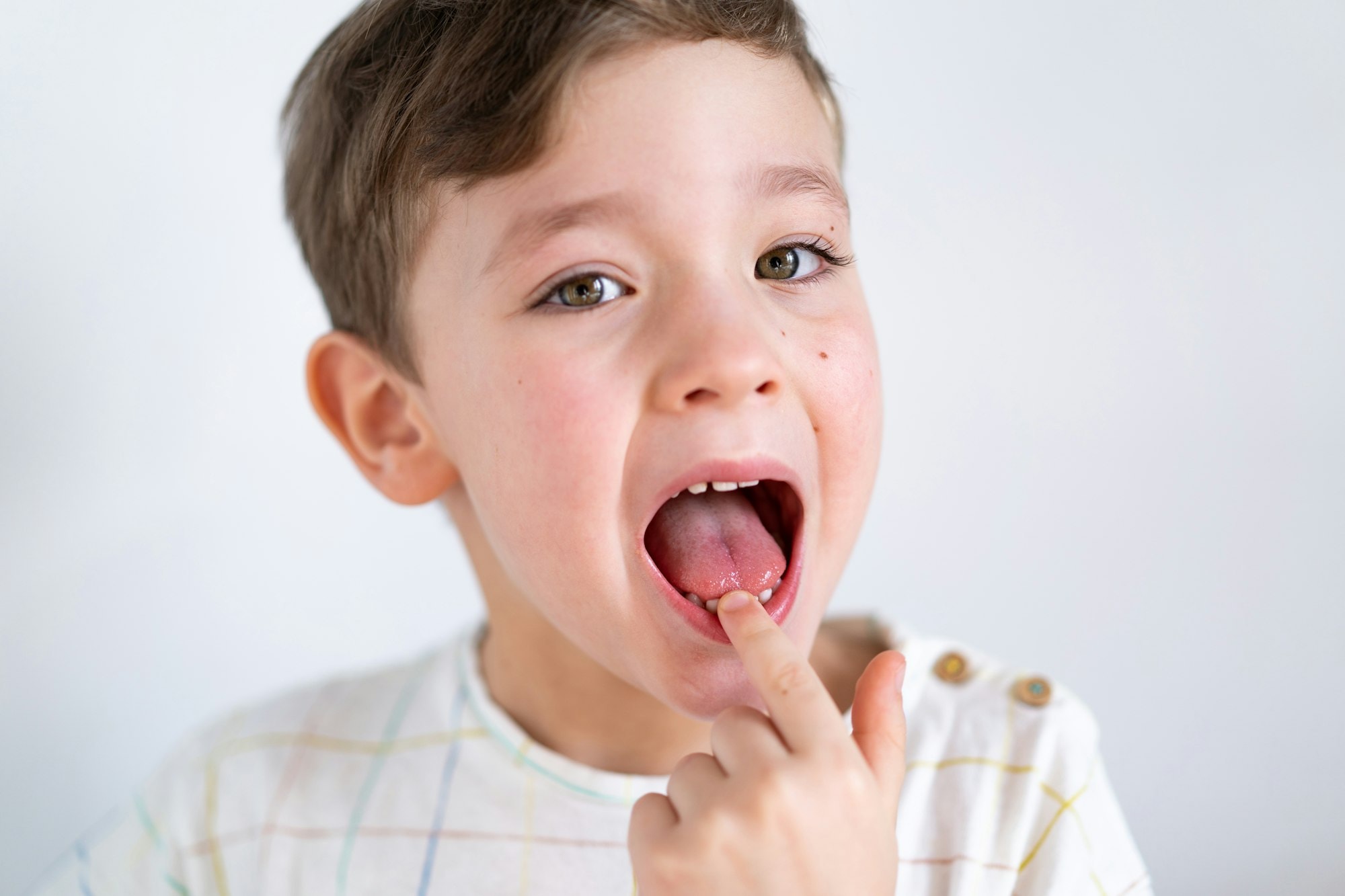 Cute boy pulling loose tooth. Process of removing a baby tooth.