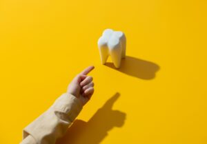 female hand points a finger at a tooth